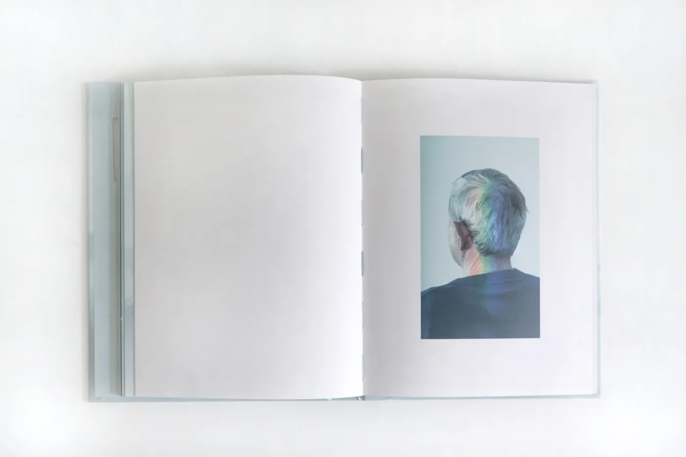 Doble página del libro: retrato de espaldas atravesado por un arcoíris de luz.